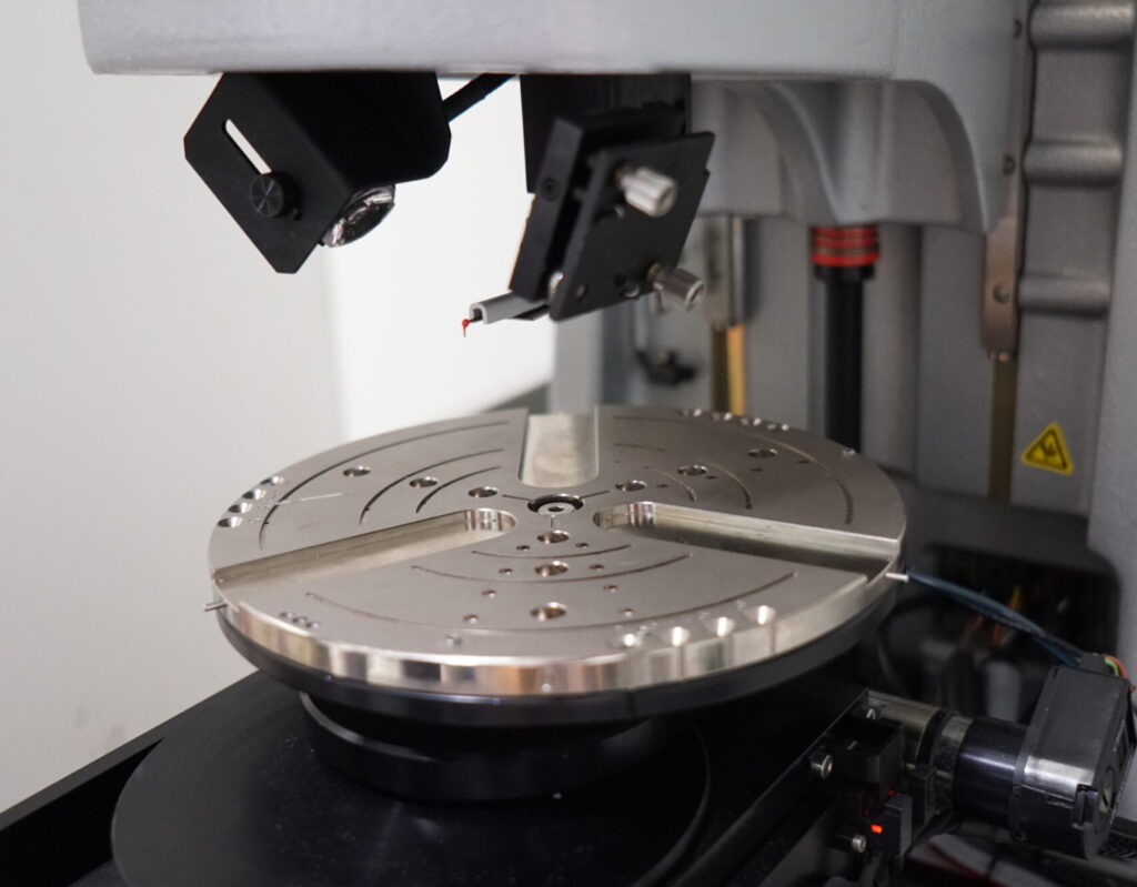 Stylus surface profilometer with diamond tip for measuring topography and roughness on large sample areas.
